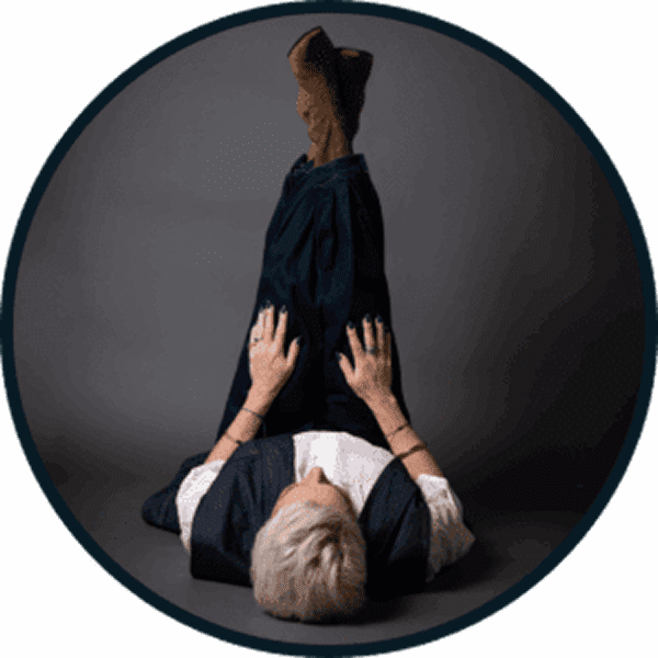 Person lying on their back with hands raised against a dark background.