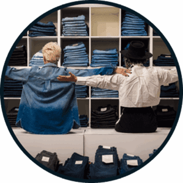 Two people browsing folded jeans in a clothing store.